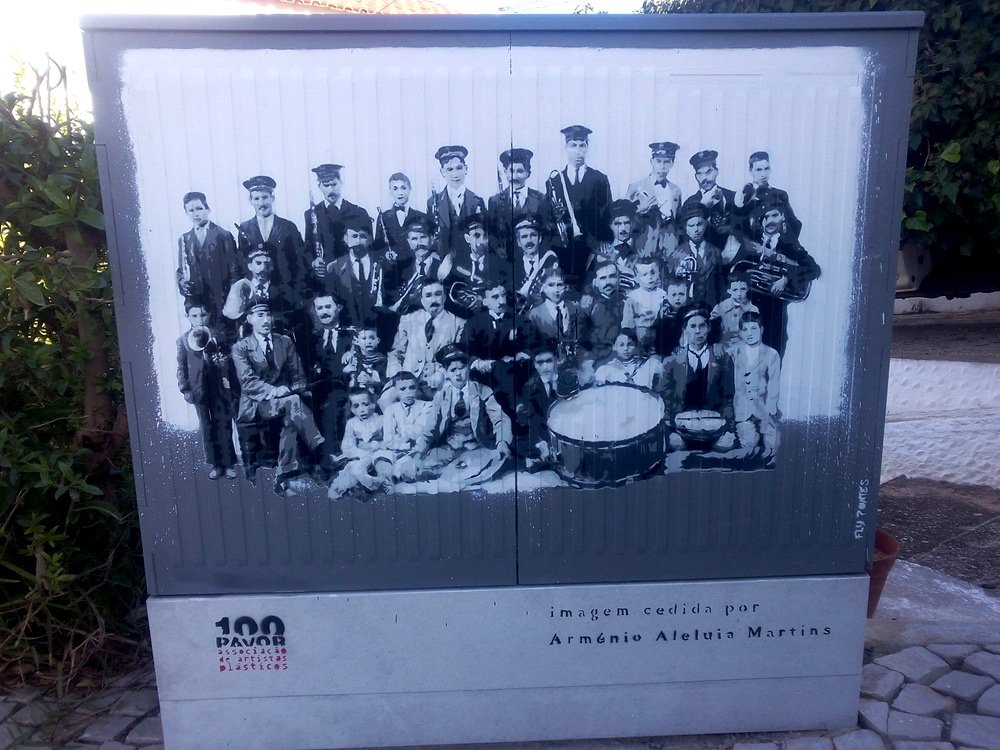 Pintura "Banda Filarmónica de Paderne" terminado num armário de electricidade em Paderne. A cena da banda é recriada integralmente em tons de cinza (monocromático) para evocar a fotografia histórica original. Técnica Stencil e Spray.