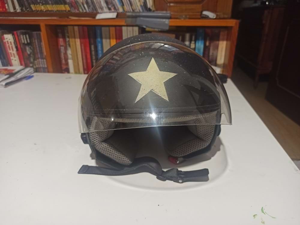 Capacete de mota personalizado com o tema 'Angel'. Apresenta um fundo texturizado criado com spray e uma grande estrela como ponto focal frontal. A arte é finalizada com verniz acrílico para durabilidade.