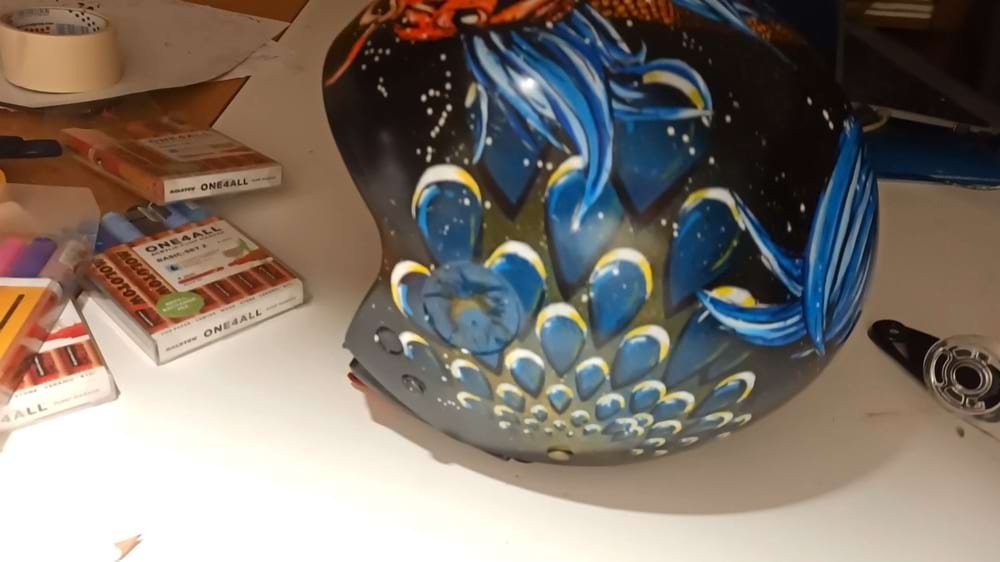 Vista lateral do capacete, mostrando a combinação de técnicas (stencil, spray e marcadores) na composição de fundo e detalhes. Cria uma composição em camadas rica em textura e dinamismo.