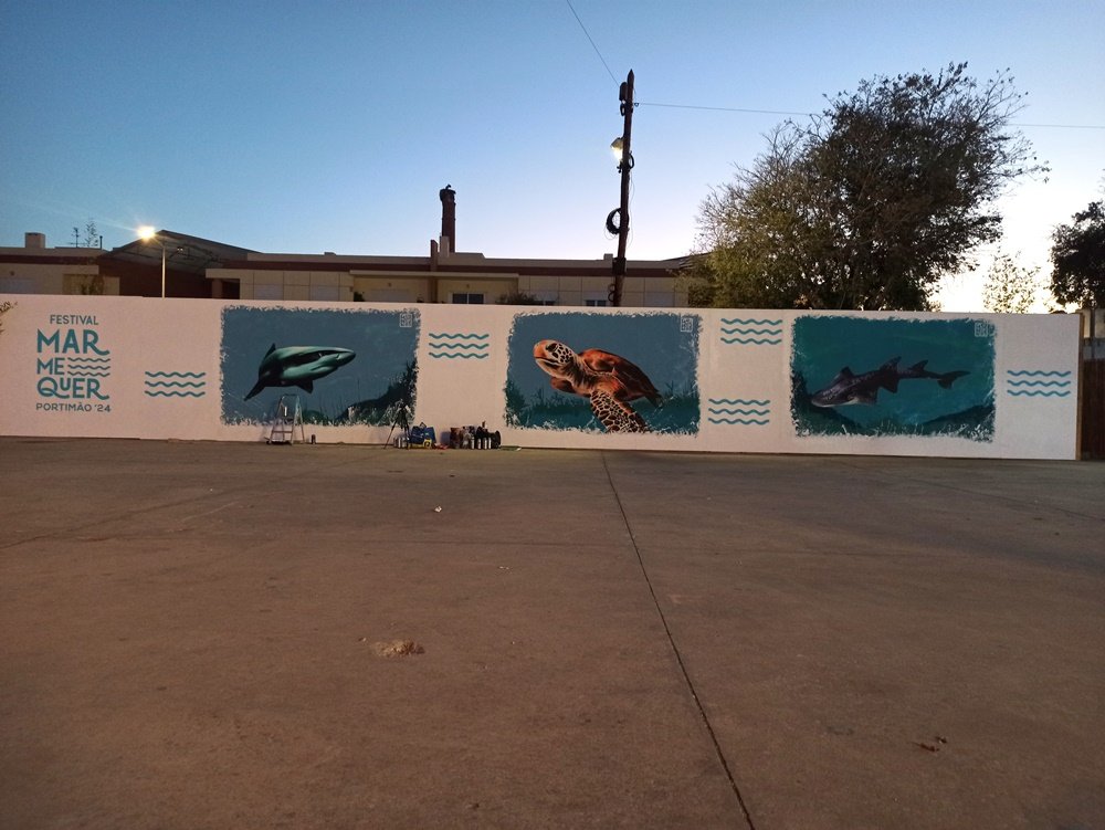 Vista panorâmica do conjunto dos três murais ("Tartaruga, Raia e Tubarão") do Festival Mar Me Quer, em Portimão. A foto capta a totalidade das obras de arte urbana que denunciam as ameaças às espécies marinhas vulneráveis.