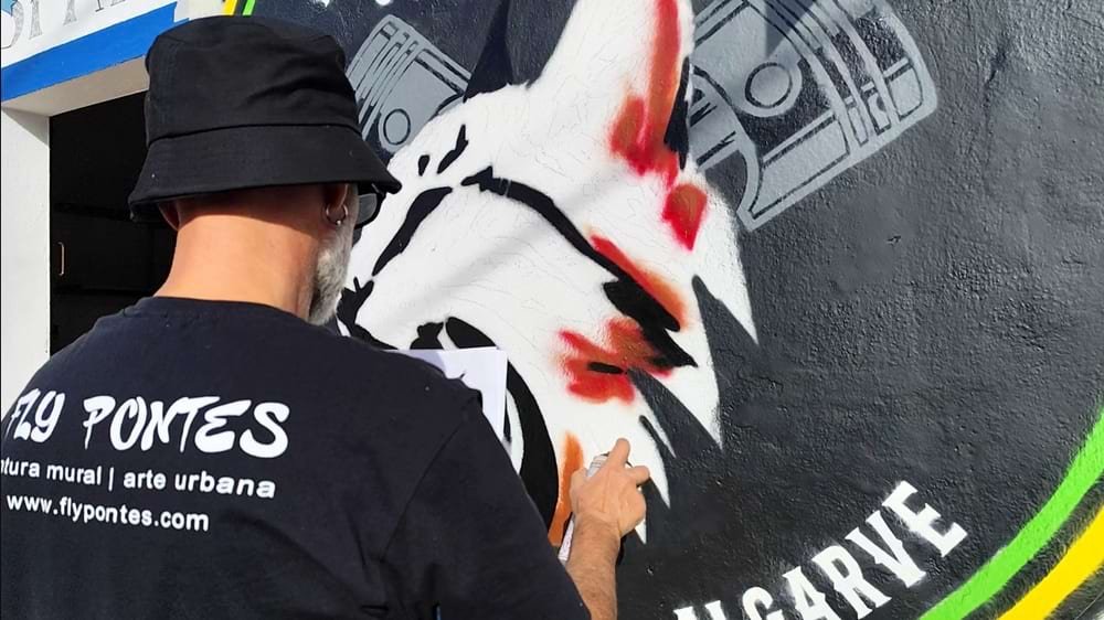 Artista a iniciar a pintura do lince no mural dos Linces Ibéricos GM. Visíveis as primeiras cores do lince e as bielas do logótipo.