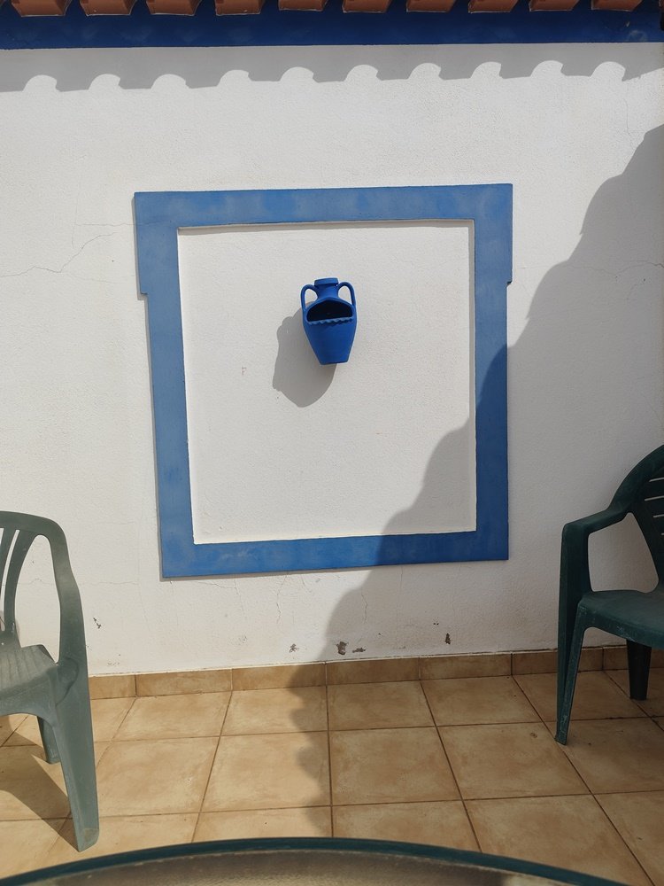 Janela falsa (tijolo ou estuque) de uma residência, com a moldura azul, antes da intervenção de arte urbana 'O Colibri na Janela Falsa'. Foto de antes e depois.