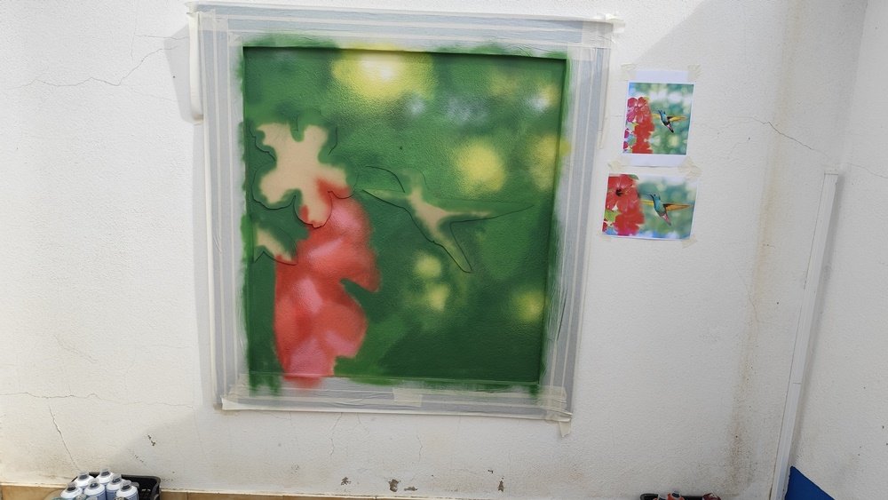 Técnica de mascaramento (masking) aplicada: Colibri e flor tapados para a pintura do fundo desfocado em spray, protegendo o trabalho já finalizado da intervenção em Janela Falsa.