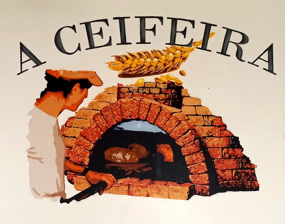 Mural do Padeiro no seu ofício, ao lado do forno onde o pão é cozido. A pintura celebra o coração da produção e o trabalho manual por trás de cada fornada da Padaria A Ceifeira.