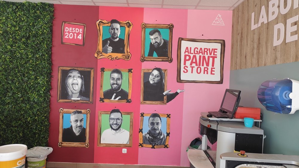 Mural "Retratos em Stencil" terminado (3,30m×2,90m) na Algarve Paint Store (Ferreiras). A obra homenageia a equipa com retratos em tons de cinza emoldurados pelas cores institucionais da marca.