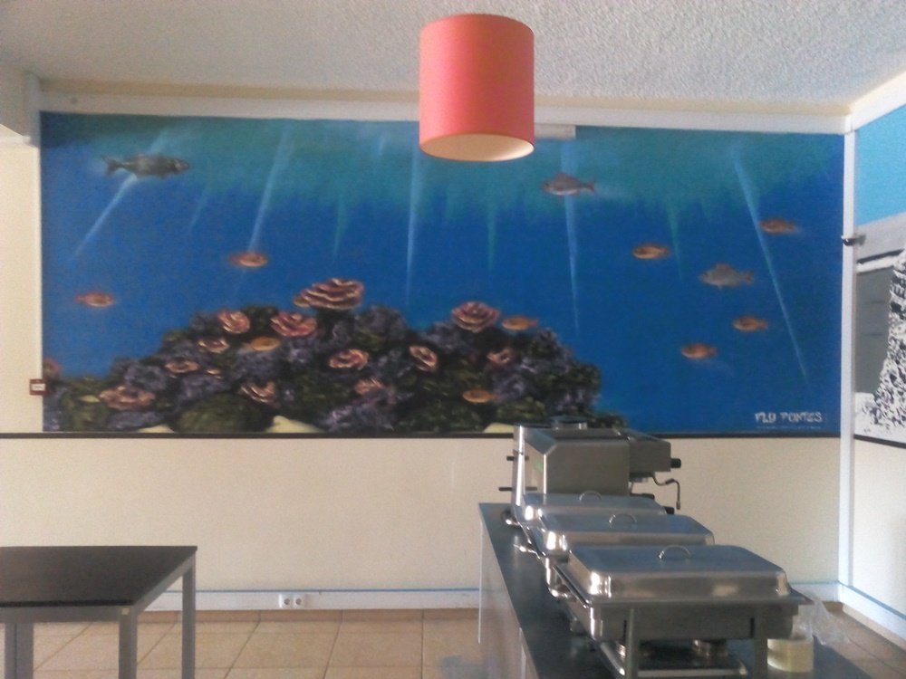 Mural "O Ecossistema Marinho Local" no restaurante do Parque de Campismo de Armação de Pêra. A obra cria uma experiência imersiva com um coral detalhado e espécies de peixes locais, celebrando a biodiversidade costeira.