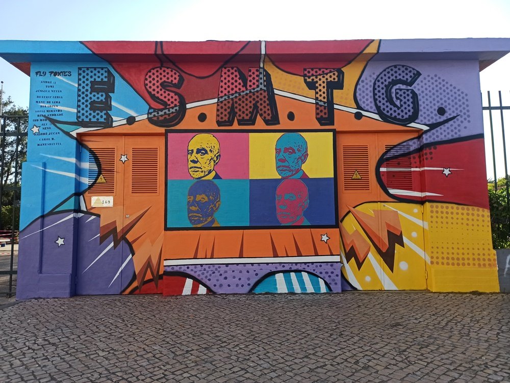 Mural Pop Art terminado no Posto de Transformação (PT) da Escola Secundária Manuel Teixeira Gomes (Portimão). A obra (6,25m×3,2m) combina o fundo Lichtenstein (pontilhados e onomatopeias) e o retrato de Manuel Teixeira Gomes estilo Warhol.
