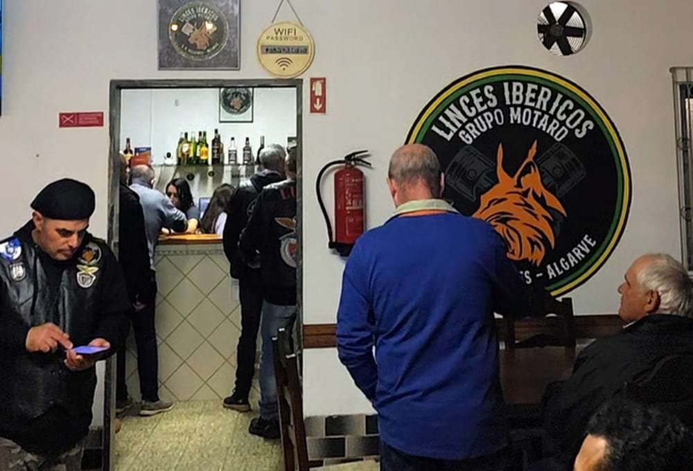 Mural do logótipo estilizado dos Linces Ibéricos GM, na parede do restaurante, com pessoas a confraternizar na inauguração da nova sede.