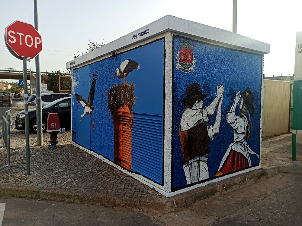 Mural na lateral do PT de Almancil, dedicado à Tradição local. O mural representa um par do rancho folclórico em trajes tradicionais. A cena, emoldurada a preto, honra a cultura e história humana da região.