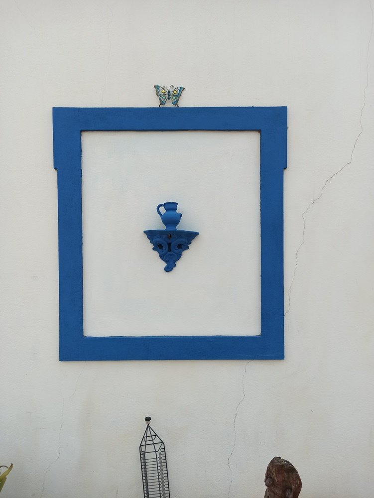 Parede branca de moradia particular antes da pintura do mural, com a ombreira da janela pintada em azul. Esta base é o ponto de partida para a criação da ilusão de óptica do Gato a espreitar.