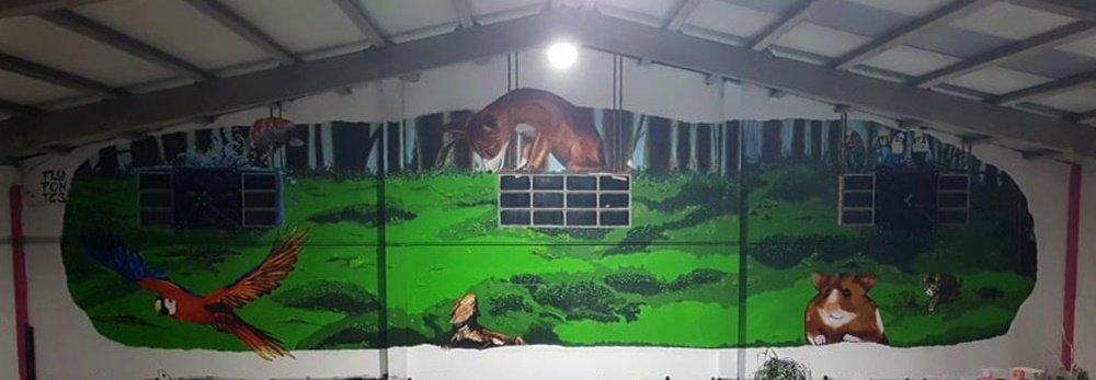 Mural imponente de 15m x 3m, "Identidade e Cor na Loja Petlandia", em Albufeira. A obra interior em tinta de água e acrílicos retrata um ecossistema colorido de animais residentes (arara, koi-fish, gato, raposa, etc.) sobre um fundo verde.