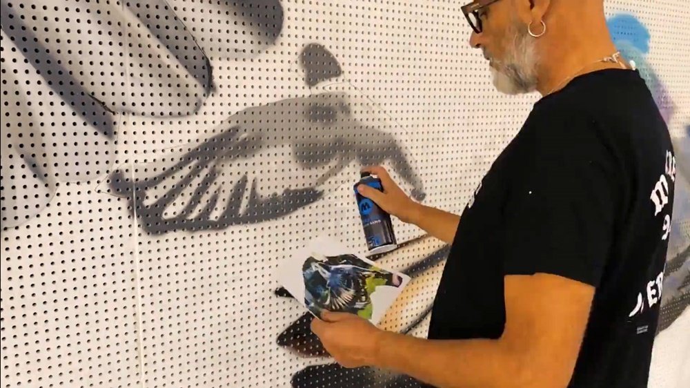 O artista Fly Pontes a pintar um dos pombos mais pequenos do mural "Tributo ao Pombo-Correio" em S. B. Messines. Com uma lata de spray numa mão e a folha de referência na outra, o artista garante a precisão do desenho.