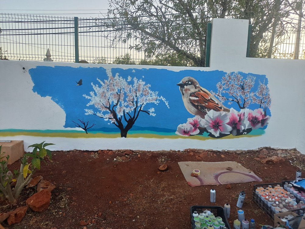 Mais de metade do mural Amendoeiras em Flor está concluído: o pardal, as flores de primeiro plano e a amendoeira mais distante. A próxima etapa é a aplicação do azul do céu e o detalhe das flores da amendoeira central, completando a paisagem de inspiração japonesa.
