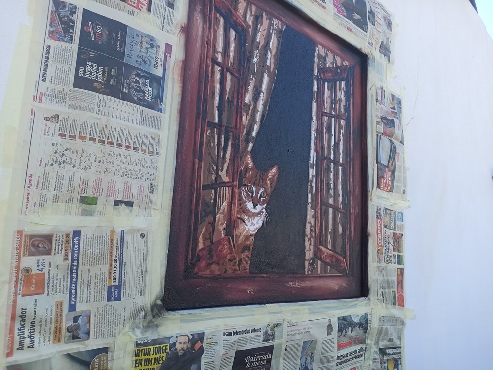 Pintura "O Gato na Janela Aberta" quase pronta, falta apenas os últimos retoques ou a remoção do isolamento. O gato, a janela e as cortinas em Stencil e Spray criam uma ilusão de óptica altamente realista numa moradia particular.