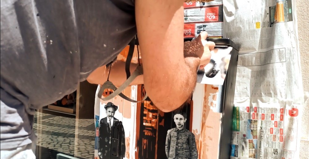 A pintura da Primeira Farmácia de Albufeira está terminada. O artista Fly Pontes a pintar a moldura preta em volta da pintura, que serve para enquadrar e realçar a obra de arte urbana.