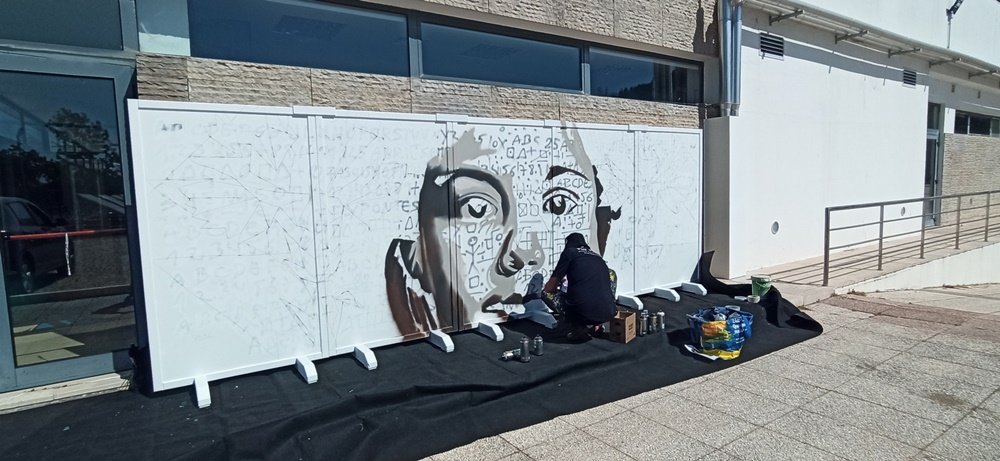 Vista de longe do mural de 5 painéis em progresso com a figura central a meio da pintura.