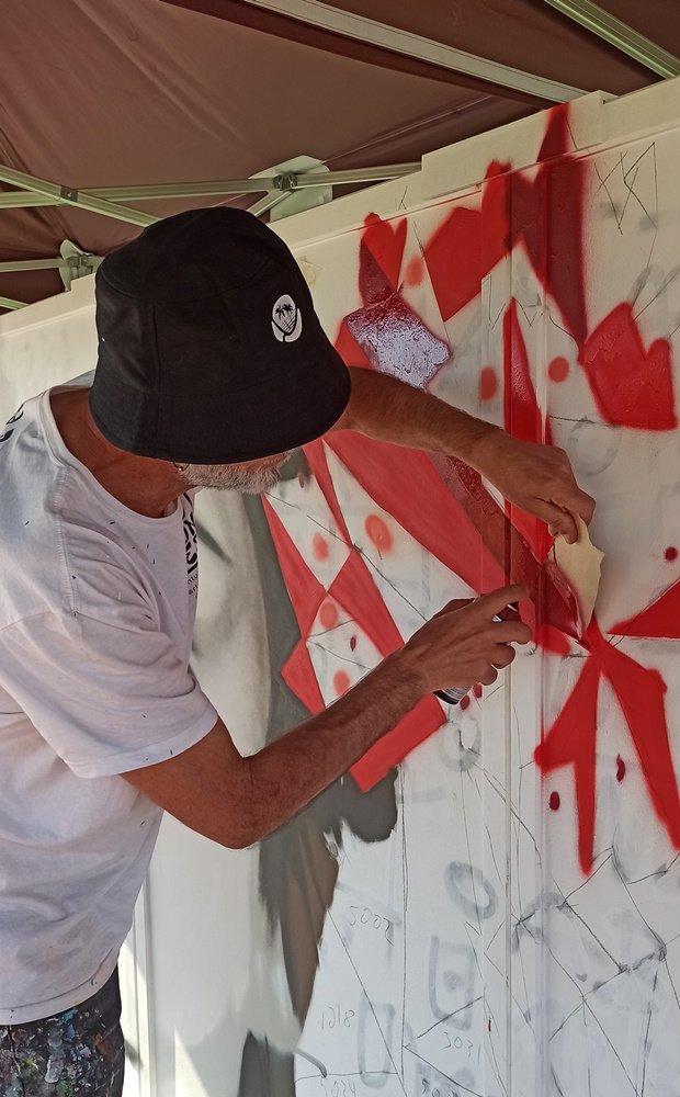 Artista Fly Pontes a usar cartolina como guia para pintar linhas retas num cravo geométrico.