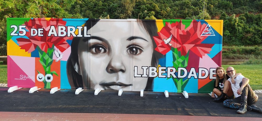 Fly Pontes e a sua companheira sentados no chão junto ao mural terminado em Silves.