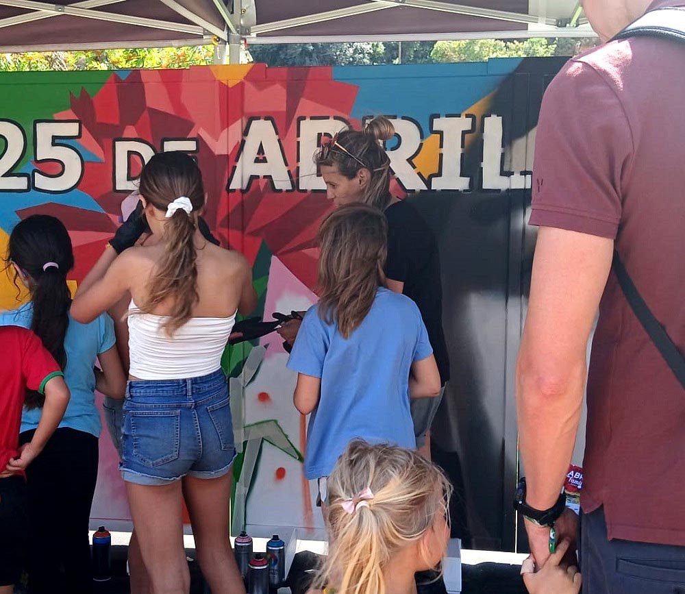 Participação comunitária em mural de arte urbana com crianças e famílias.