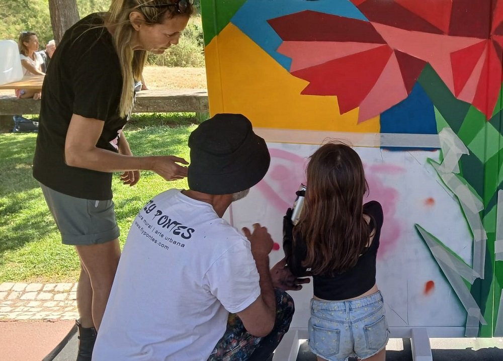 Detalhe de criança a pintar ilustração original com spray sob orientação do artista.
