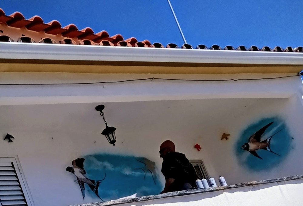 parede de varanda mostrando uma andorinha acabada de revelar e outra ainda coberta por papel de stencil.