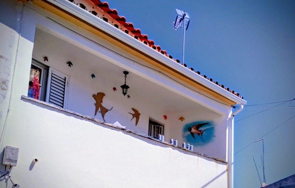 vista da rua de uma varanda em obras com latas de spray e pinturas de pássaros tapadas com moldes.