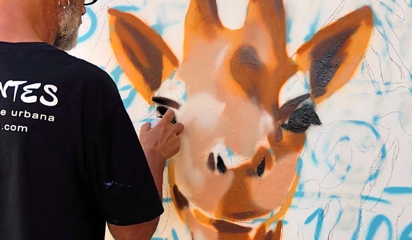 Pintura em progresso do rosto realista de uma girafa feito a spray numa parede exterior em Messines, Algarve.